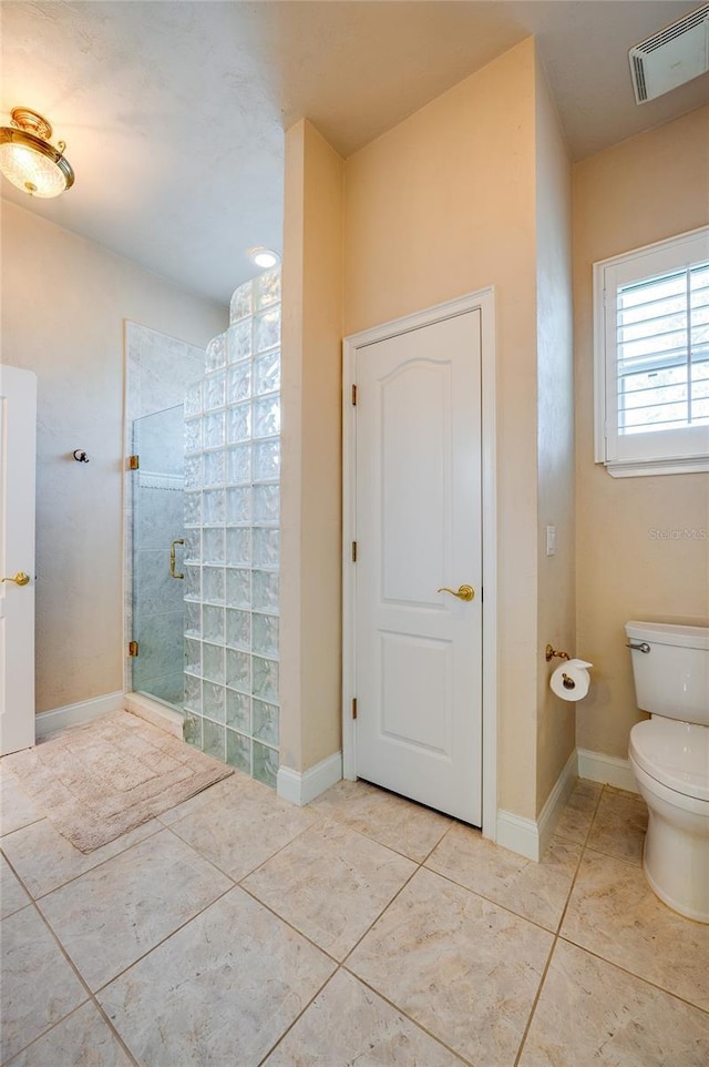 bathroom with tile patterned flooring, visible vents, baseboards, toilet, and a tile shower