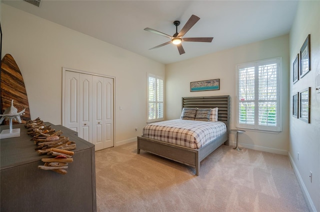 bedroom featuring baseboards, light carpet, a closet, and ceiling fan