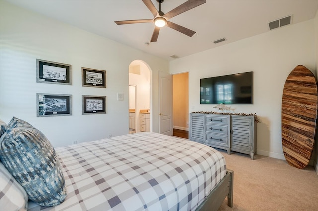 bedroom with arched walkways, visible vents, light colored carpet, and baseboards