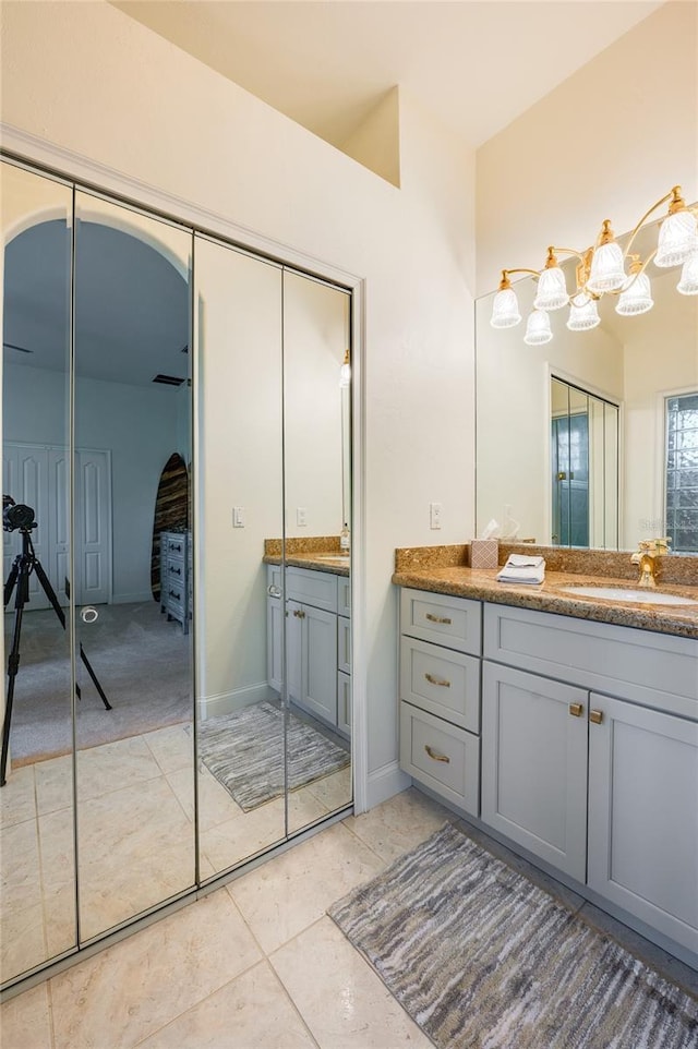 full bathroom featuring tile patterned flooring, two vanities, baseboards, and a sink