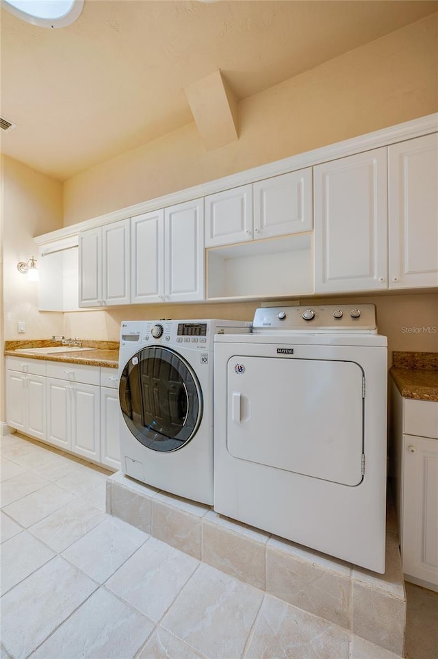 laundry area featuring a sink, cabinet space, light tile patterned floors, and washing machine and clothes dryer