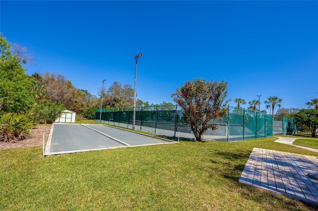 view of sport court with a yard, an outdoor structure, and fence