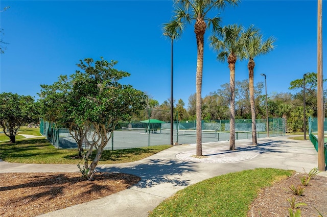 view of property's community with a tennis court and fence