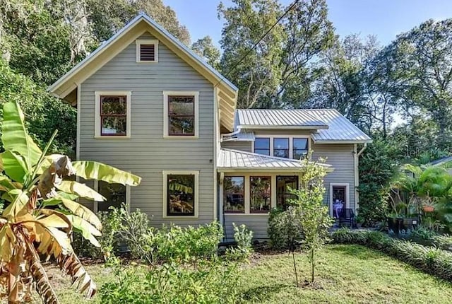 rear view of property featuring metal roof and a yard