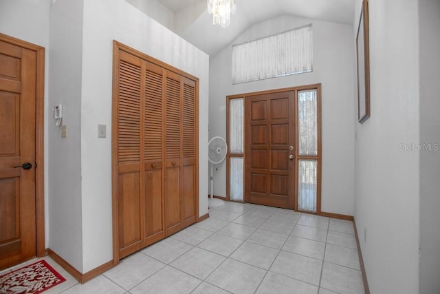 foyer featuring light tile patterned floors, baseboards, and high vaulted ceiling