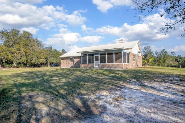 rear view of property featuring a yard, a sunroom, and a chimney