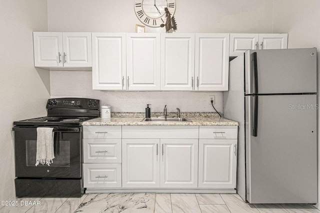 kitchen with a sink, black / electric stove, white cabinetry, and freestanding refrigerator