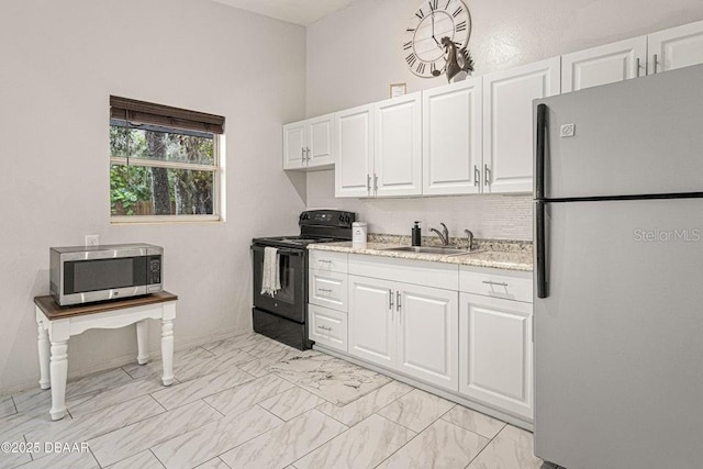 kitchen featuring marble finish floor, a sink, appliances with stainless steel finishes, white cabinets, and light stone countertops