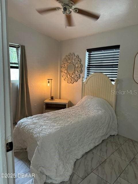 bedroom with marble finish floor and ceiling fan