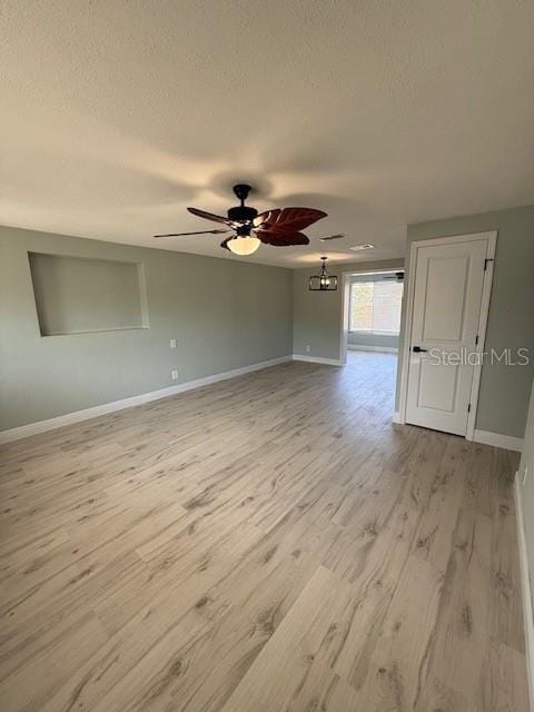 spare room featuring light wood-type flooring, baseboards, a textured ceiling, and a ceiling fan