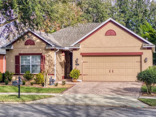 view of front of house featuring stucco siding, decorative driveway, a garage, and roof with shingles