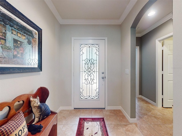 foyer entrance with crown molding, light tile patterned floors, baseboards, and arched walkways