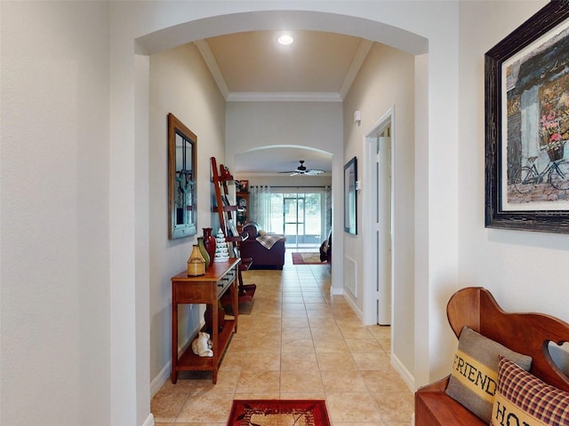 hallway with arched walkways, crown molding, and baseboards