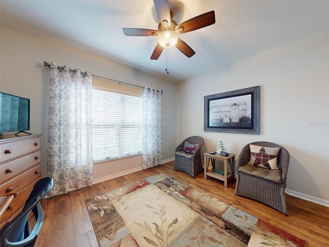 sitting room featuring baseboards, wood-type flooring, and a ceiling fan