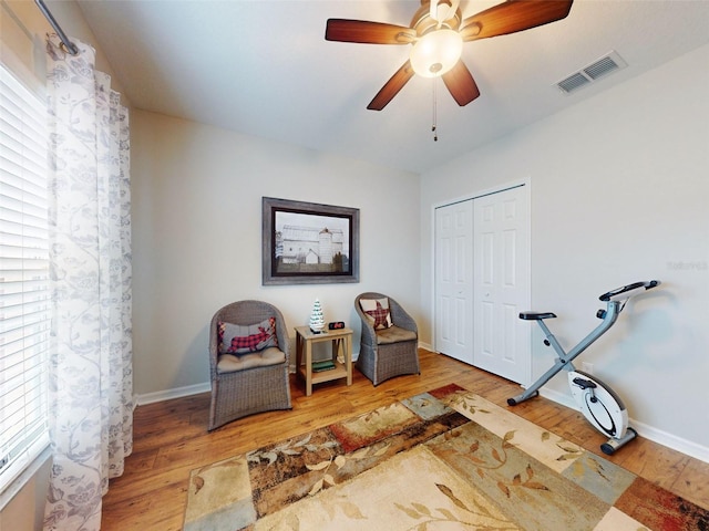 living area with visible vents, baseboards, ceiling fan, and wood finished floors