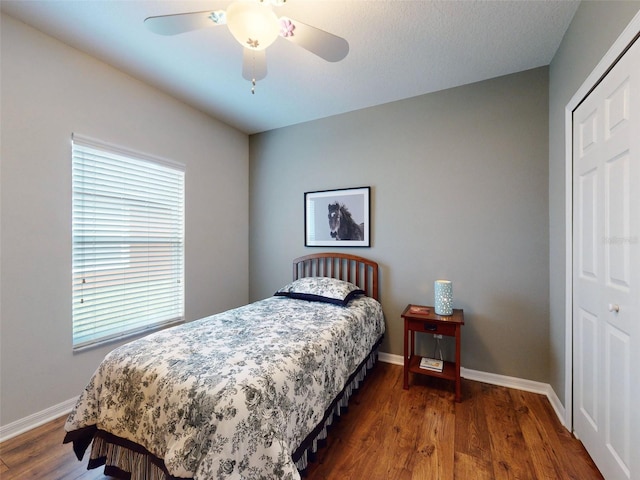 bedroom with ceiling fan, a closet, baseboards, and wood finished floors