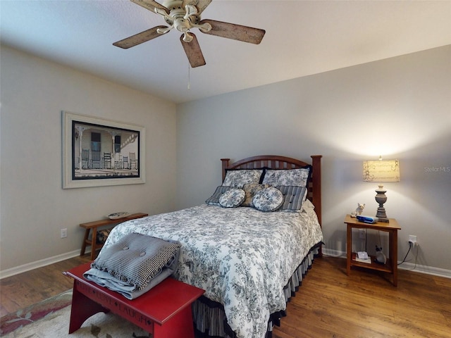 bedroom featuring baseboards, wood finished floors, and a ceiling fan