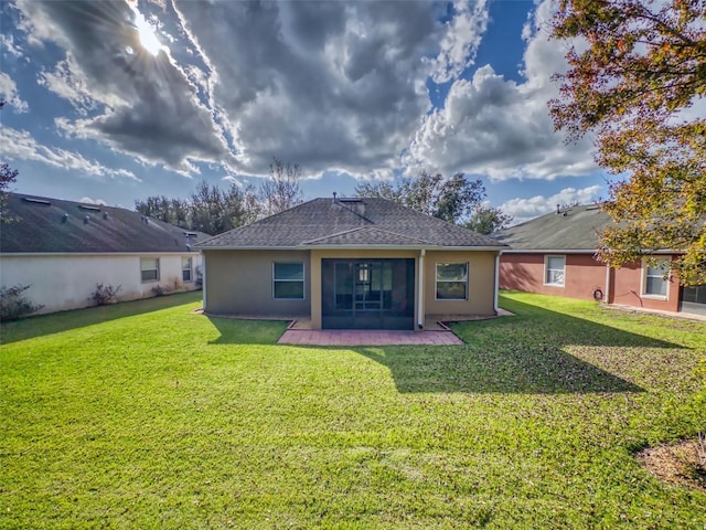 rear view of house with a patio area, a lawn, roof with shingles, and stucco siding