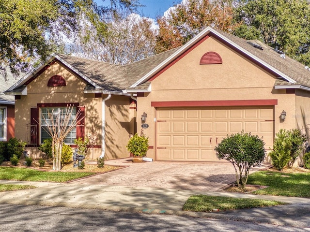 view of front of house with stucco siding, an attached garage, and decorative driveway