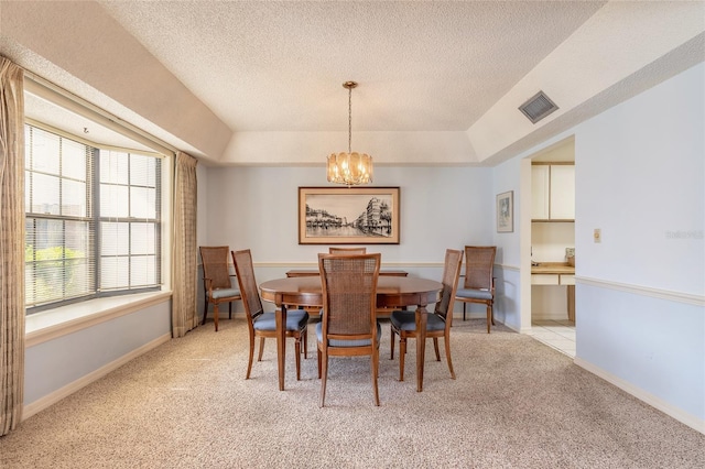 dining space featuring visible vents, a tray ceiling, a textured ceiling, light colored carpet, and a chandelier