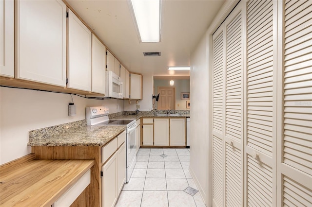 kitchen with visible vents, light tile patterned floors, white appliances, white cabinetry, and a sink