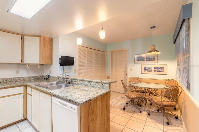 kitchen with light tile patterned floors, white cabinetry, a peninsula, a sink, and dishwasher