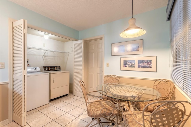 laundry area with light tile patterned floors, a textured ceiling, laundry area, and washing machine and clothes dryer