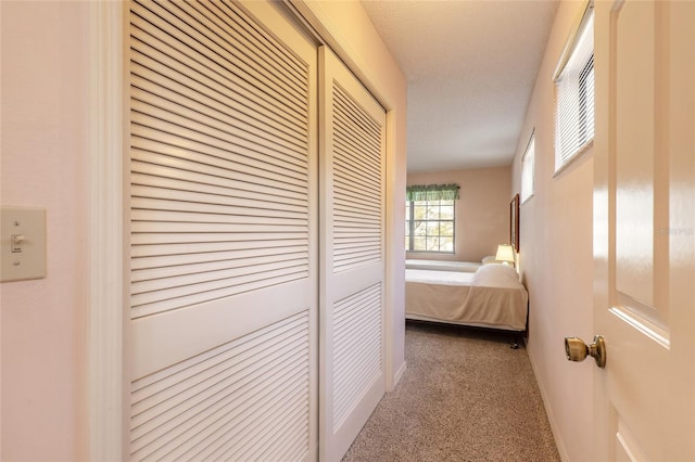 hallway featuring carpet and baseboards