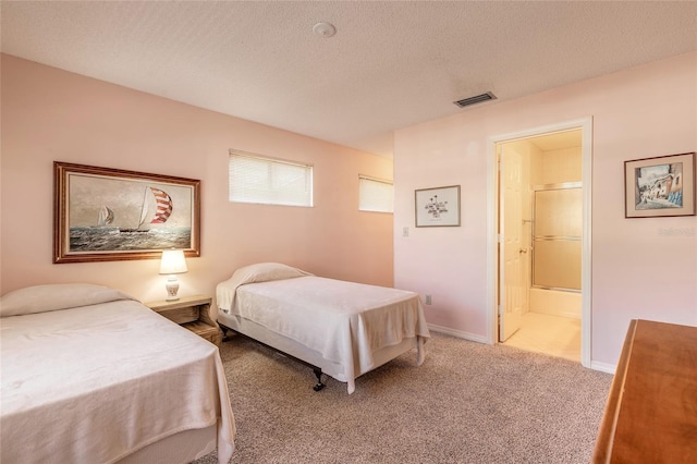 carpeted bedroom featuring visible vents, baseboards, a textured ceiling, and ensuite bathroom