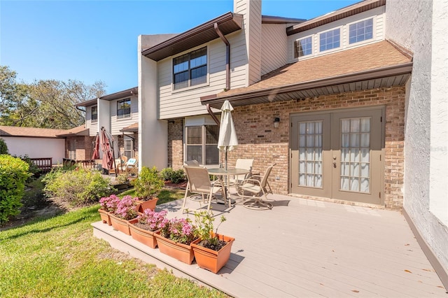 back of house with a deck, french doors, brick siding, and a chimney