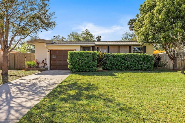 view of front of property featuring concrete driveway, fence, a garage, and a front yard