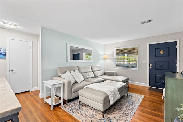 living area featuring wood finished floors, visible vents, and baseboards