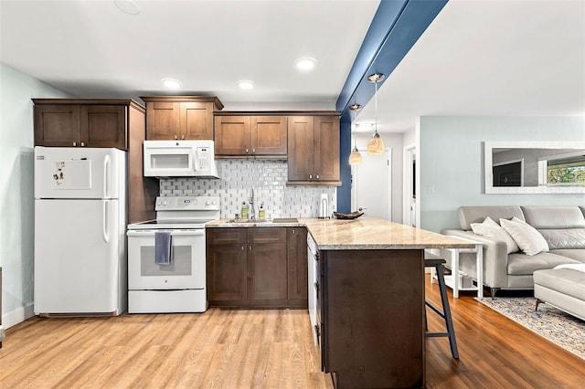 kitchen with white appliances, light wood finished floors, a peninsula, open floor plan, and backsplash