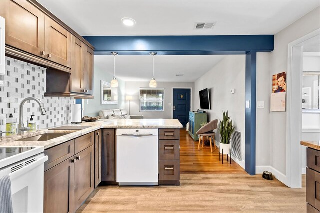 kitchen featuring visible vents, a sink, a peninsula, white dishwasher, and light wood finished floors