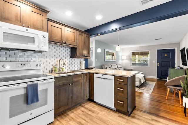 kitchen with decorative backsplash, white appliances, light wood-style flooring, and a peninsula