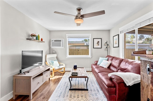 living area featuring a wealth of natural light, a wall mounted AC, ceiling fan, and wood finished floors