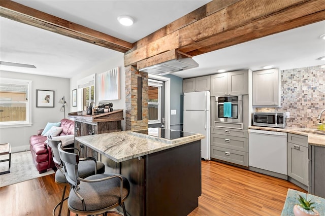 kitchen with gray cabinetry, beam ceiling, light wood-style flooring, appliances with stainless steel finishes, and a sink