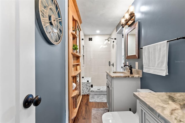 full bath with vanity, a shower stall, toilet, and wood finished floors