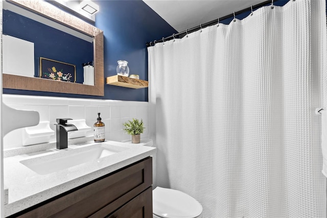 full bath with vanity, tile walls, and toilet