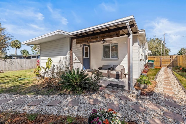 rear view of property with a gate, a lawn, a ceiling fan, and fence