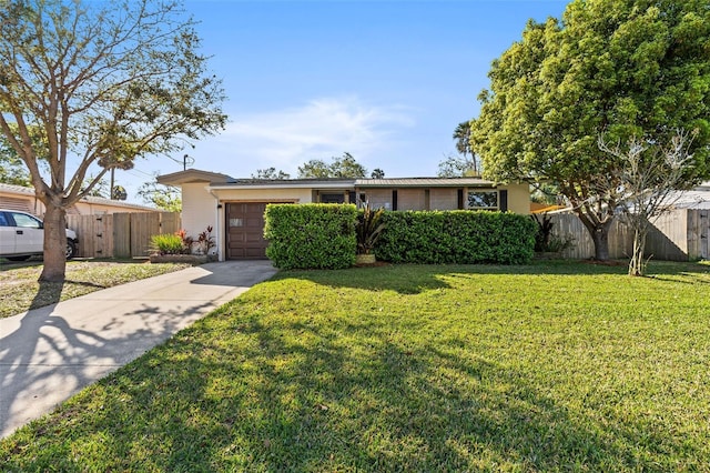 view of front of home with a garage, concrete driveway, a front lawn, and fence