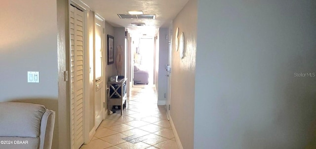 hallway featuring light tile patterned flooring, baseboards, and visible vents