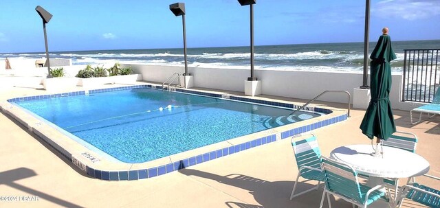 pool featuring a patio area and a water view