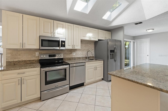 kitchen featuring a sink, light tile patterned floors, stone countertops, and stainless steel appliances