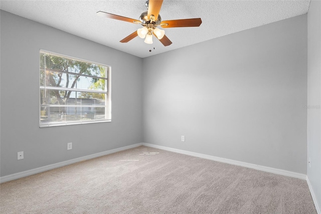 spare room with a textured ceiling, carpet, baseboards, and ceiling fan