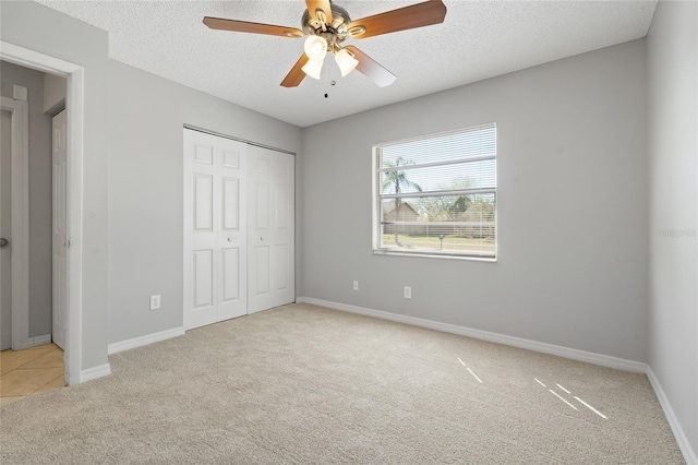 unfurnished bedroom featuring baseboards, carpet floors, ceiling fan, a closet, and a textured ceiling