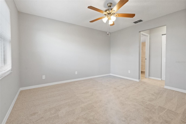 unfurnished room featuring baseboards, a ceiling fan, visible vents, and light carpet