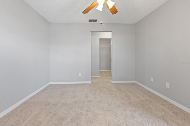 unfurnished room with visible vents, baseboards, ceiling fan, light colored carpet, and a textured ceiling