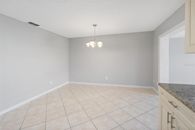 unfurnished room with light tile patterned floors, baseboards, visible vents, an inviting chandelier, and a textured ceiling