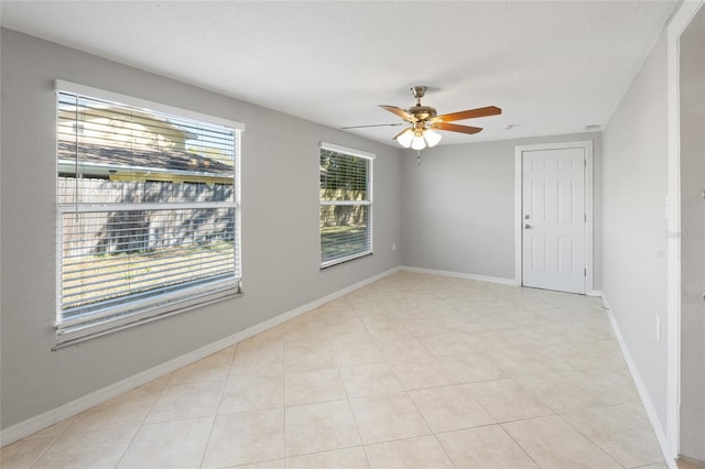 spare room with light tile patterned floors, a textured ceiling, baseboards, and a ceiling fan